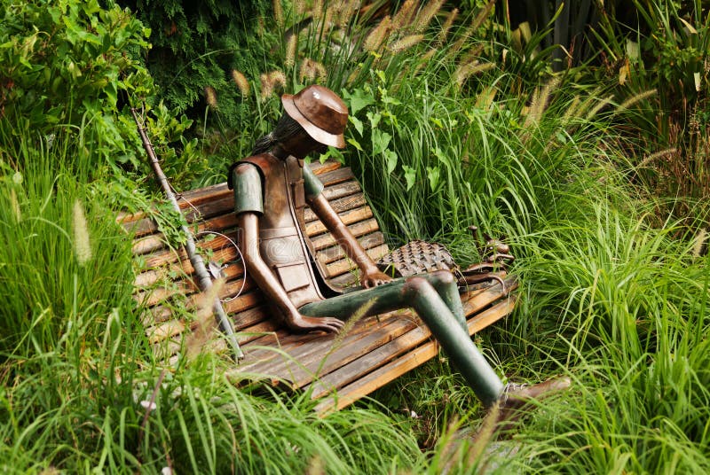TURIN, ITALY - JULY 12, 2016: Urban sculpture by Rodolfo Marasciuolo of a fisherman with fishing rod, basket and cat on a bench o. F Valentino`s Park in Turin royalty free stock photos TURIN, ITALY - JULY 12, 2016: Urban sculpture by Rodolfo Marasciuolo of a fisherman with fishing rod, basket and cat on a bench o. F Valentino`s Park in Turin royalty free stock photos