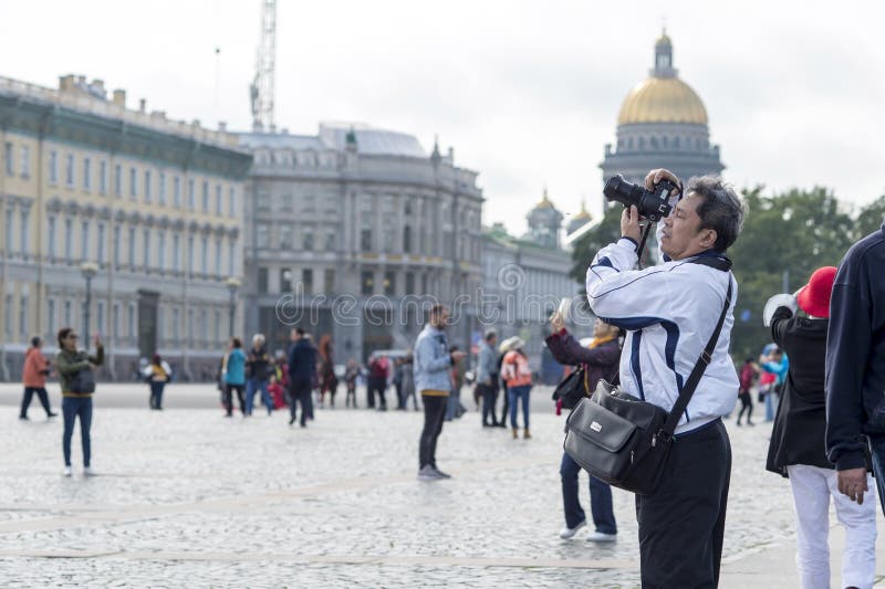 Turist- asiatiska utseendemässiga fotografier för man på kameradragningar på slottfyrkanten av St Petersburg, Ryssland, September arkivbilder Turist- asiatiska utseendemässiga fotografier för man på kameradragningar på slottfyrkanten av St Petersburg, Ryssland, September arkivbilder