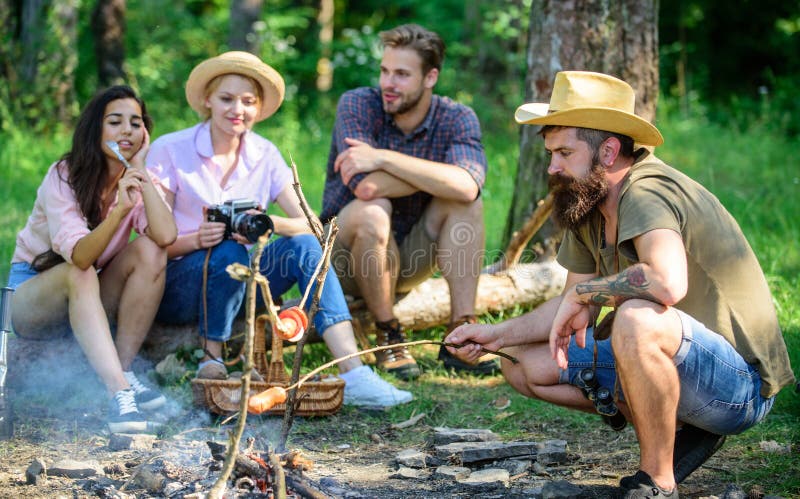 Turist- avslappnande near brasa för vängrupp Turister som har mellanmåltid med grillat över brandmat Grilla för Hipster arkivfoton Turist- avslappnande near brasa för vängrupp Turister som har mellanmåltid med grillat över brandmat Grilla för Hipster arkivfoton
