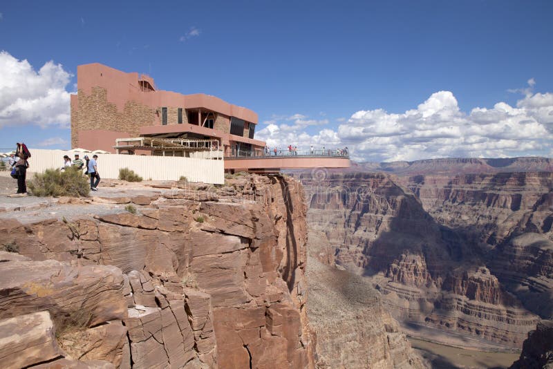 Turist som tycker om sikten av den västra kanten av Grand Canyon från Skywalken royaltyfria foton Turist som tycker om sikten av den västra kanten av Grand Canyon från Skywalken royaltyfria foton