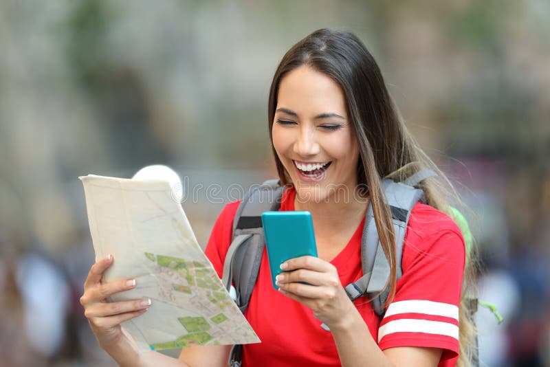 Turista adolescente que usa un teléfono y sosteniendo un mapa