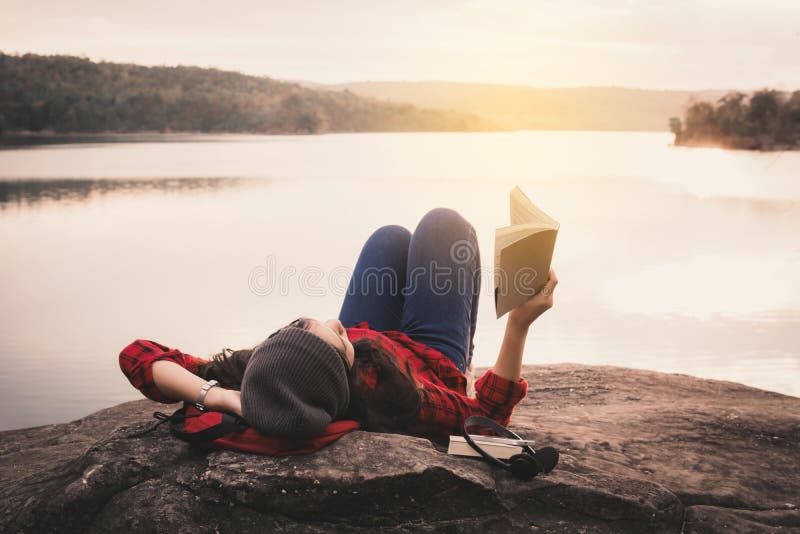 Turista asiático de relaxamento do momento que lê um livro na rocha fotografia de stock royalty free Turista asiático de relaxamento do momento que lê um livro na rocha fotografia de stock royalty free