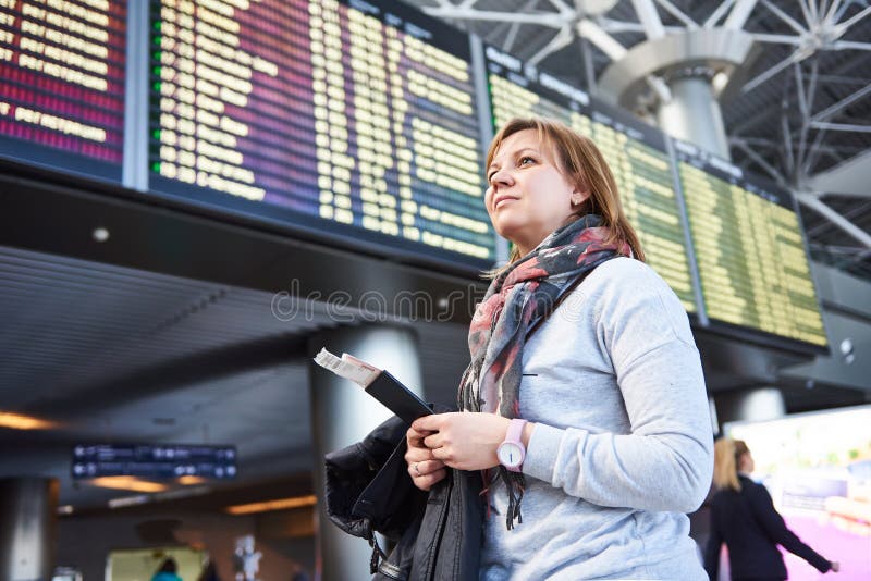 Turista da mulher que está no aeroporto no fundo das partidas imagens de stock Turista da mulher que está no aeroporto no fundo das partidas imagens de stock