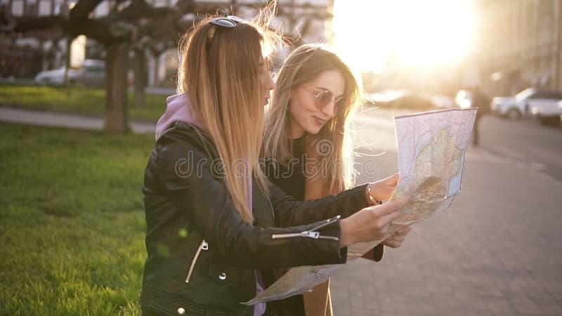 Turista de duas meninas na roupa ocasional, apreciando suas aventuras na cidade nova Guia do curso, turismo em Europa com amigos