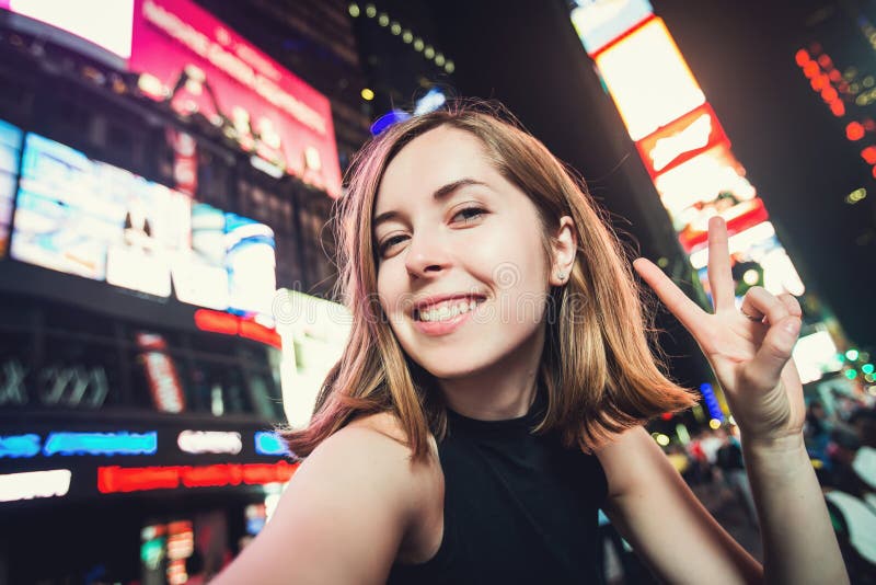 Turista de la mujer joven que ríe y que toma la foto del selfie en New York City, Manhattan, Times Square imagenes de archivo