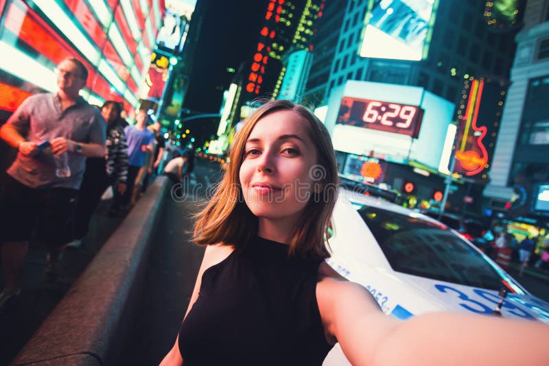 Turista de la mujer joven que ríe y que toma la foto del selfie en New York City, Manhattan, Times Square imagenes de archivo