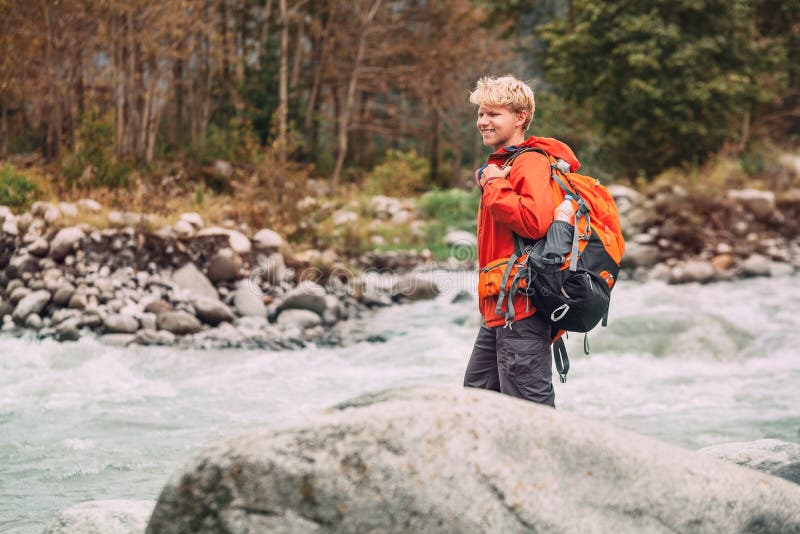 Turista del giovane nella foresta della montagna sulla sponda del fiume fotografia stock Turista del giovane nella foresta della montagna sulla sponda del fiume fotografia stock