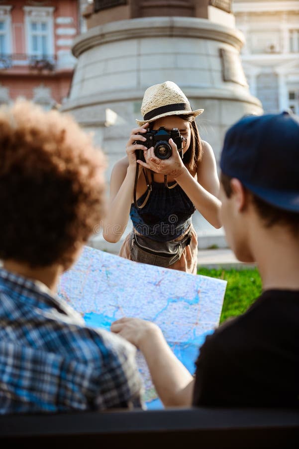 Turista fêmea bonito novo que toma a imagem de seus amigos foto de stock Turista fêmea bonito novo que toma a imagem de seus amigos foto de stock