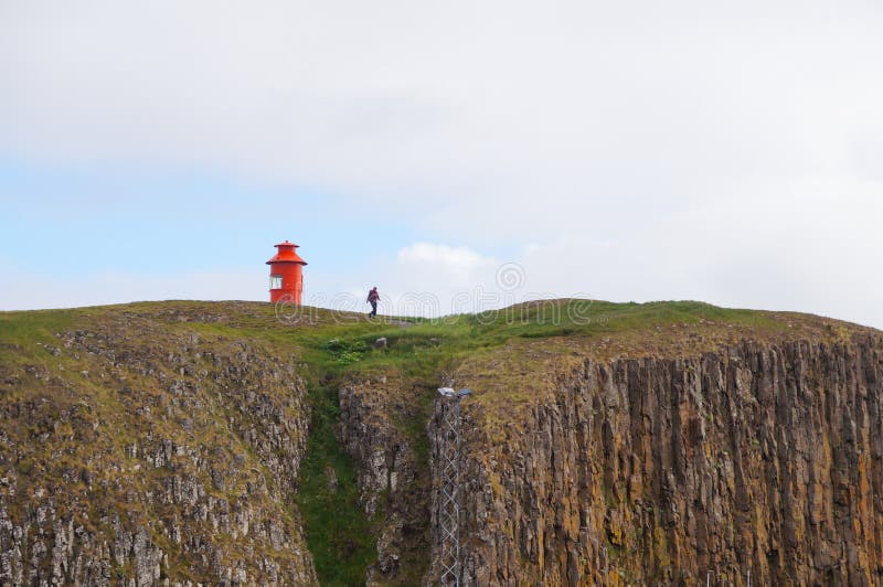 Turista non identificato che cammina giù dalla scogliera in Stykkisholmur, Islanda fotografie stock Turista non identificato che cammina giù dalla scogliera in Stykkisholmur, Islanda fotografie stock