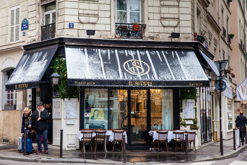 Turistas com bagagem ao lado de um restaurante italiano em um canto bonito de Paris no inverno imagens de stock royalty free