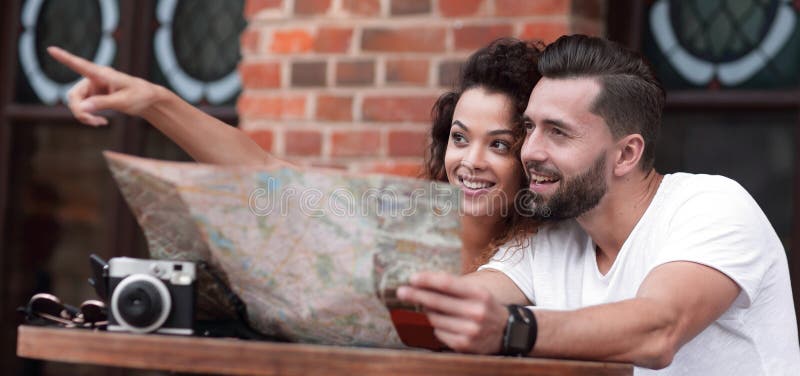 Turistas novos que comem o café no café e que leem o mapa fotografia de stock Turistas novos que comem o café no café e que leem o mapa fotografia de stock
