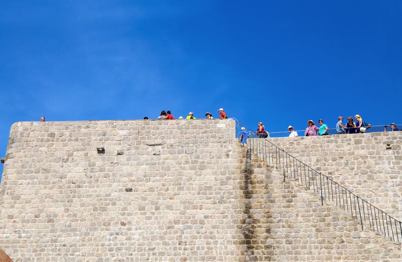 Turistas que estão nas paredes velhas da cidade de DUrovnik, Dalmácia, Croácia fotografia de stock Turistas que estão nas paredes velhas da cidade de DUrovnik, Dalmácia, Croácia fotografia de stock