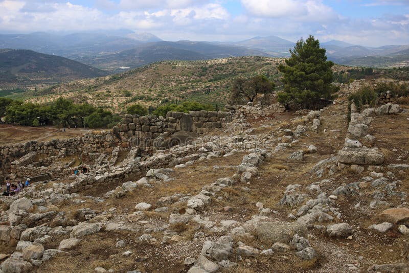 Turister går till och med porten för lejon` s av den Mycenae citadellen royaltyfri foto Turister går till och med porten för lejon` s av den Mycenae citadellen royaltyfri foto