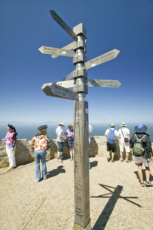 Turisti che esaminano vista del punto del capo, il Capo di Buona Speranza, fuori di Cape Town, del Sudafrica e del segno indicant fotografia stock libera da diritti Turisti che esaminano vista del punto del capo, il Capo di Buona Speranza, fuori di Cape Town, del Sudafrica e del segno indicant fotografia stock libera da diritti