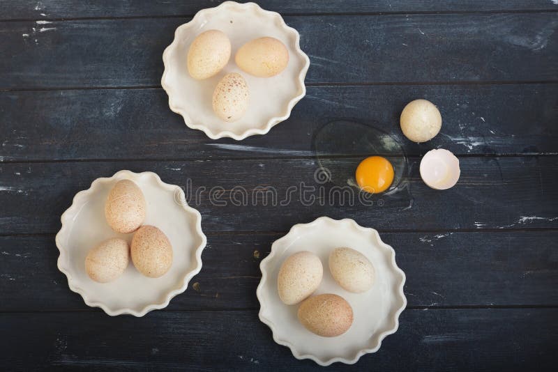 Turkey Eggs in Three White Dishes and One Broken Egg on Rough Dyed