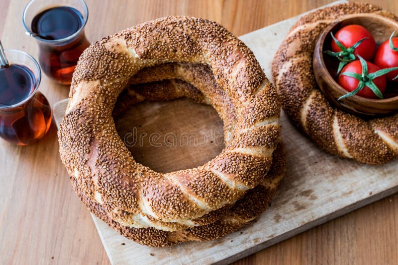 Turkish Bagel Simit with tea and cherry tomatoes on wooden surface. stock photo
