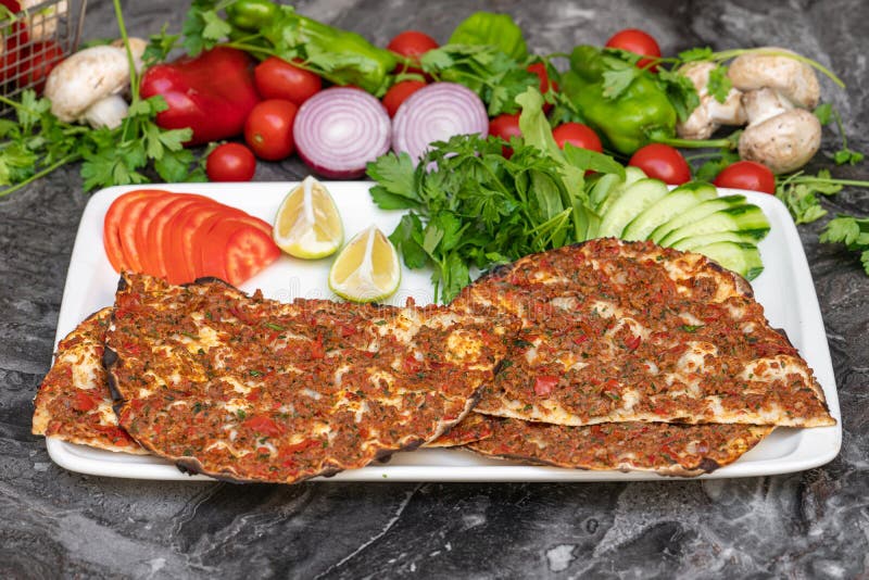 Turkish Lahmacun or Turkish pizza with tomato, parsley and lemon on marble table royalty free stock image