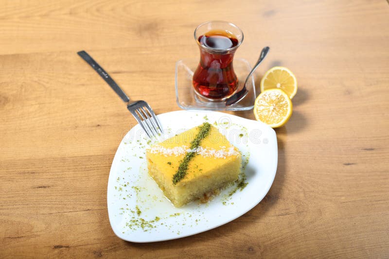 Turkish traditional desser Revani on white plate with tea. Turkish traditional desser Revani on white plate with tea