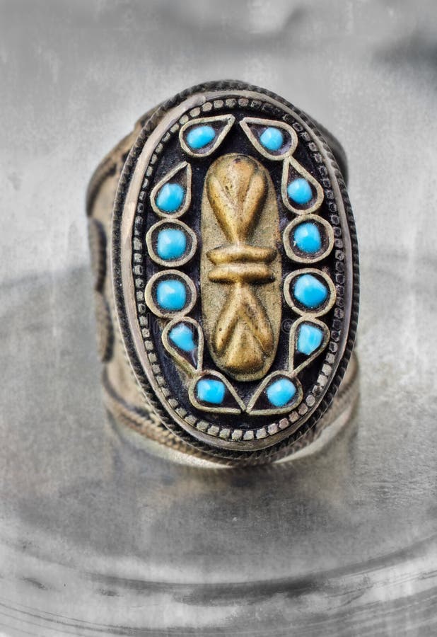 Over 100 years old antique Turkish tribal ring with grunge pattern and blue stones on textured background.