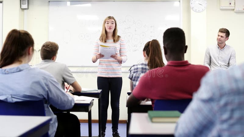 Turma da escola secundária de Giving Presentation To do estudante fêmea na lição da ciência