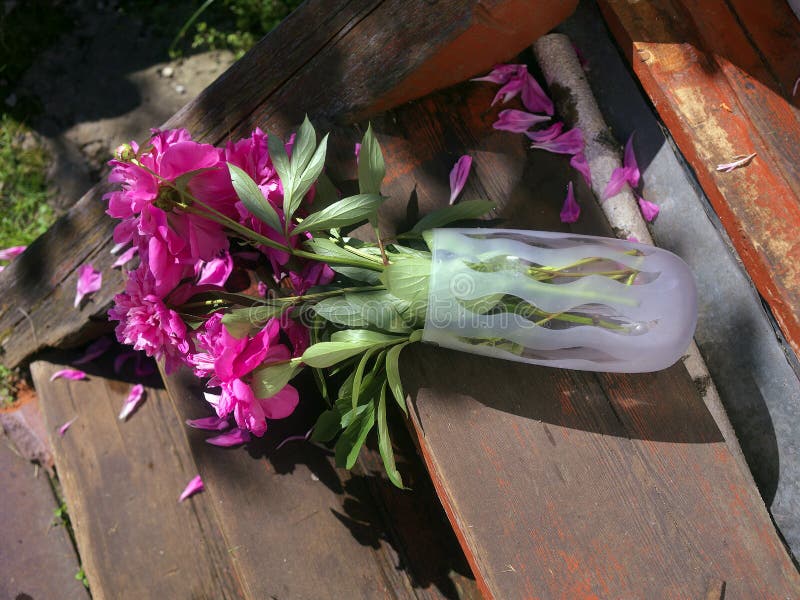 Awkwardly turned over vase with flowers on the wooden steps