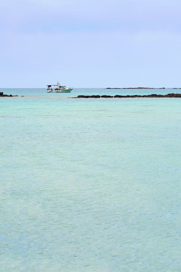 Turquoise blue sea water on a lagoon with a ship on a horizon line ander a cloudy sky. Copy space.