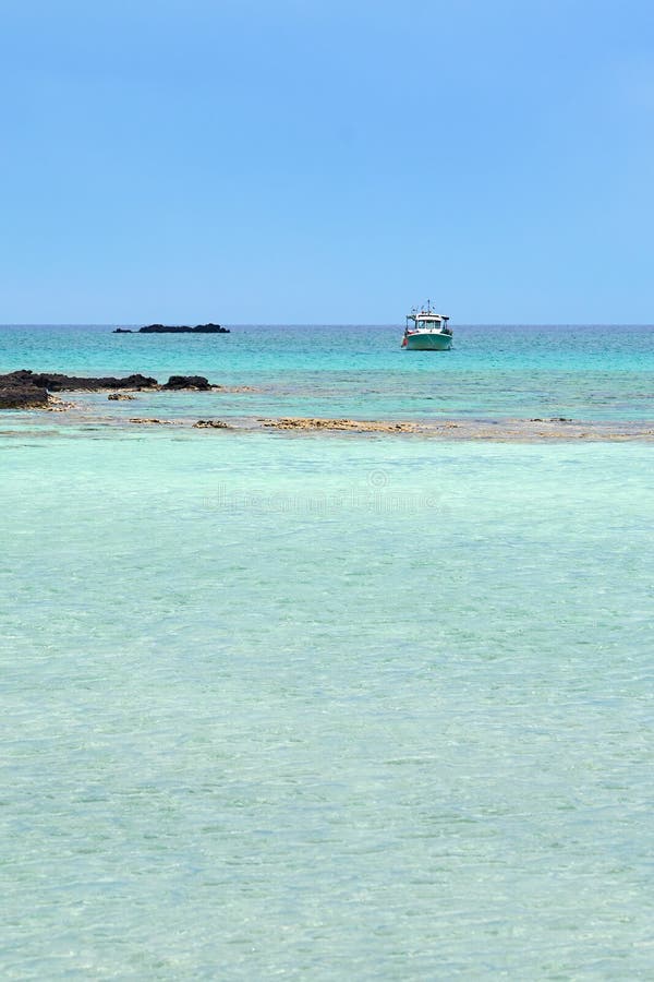 Turquoise blue sea water on a lagoon with a ship on a horizon line ander a cloudy sky. Copy space.