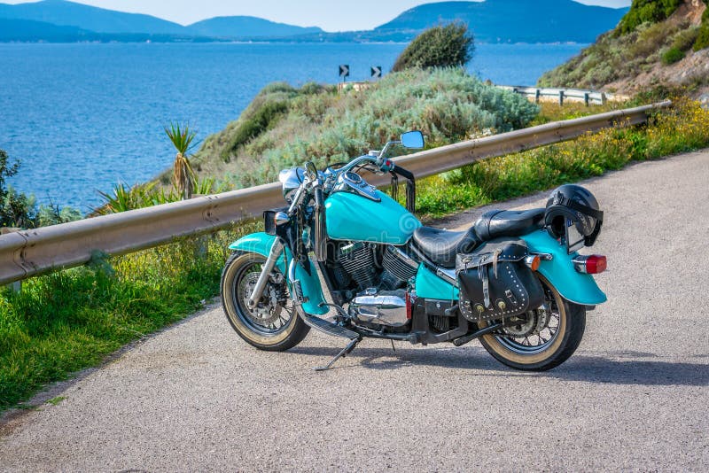 Turquoise classic motorcycle parked by the sea royalty free stock photography