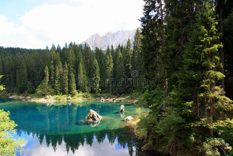 Carezza lake and Sella mountain group, green pines forest. Trentino Alto Adige, Italy. Carezza lake and Sella mountain group, green pines forest. Trentino Alto Adige, Italy