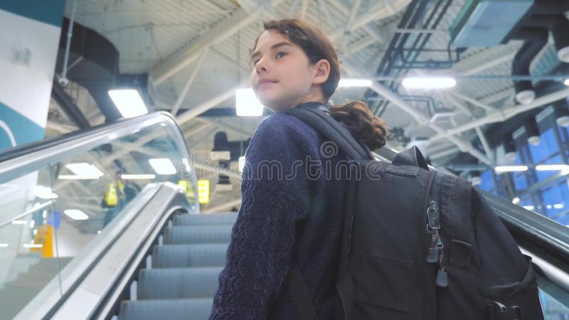 Turystyczna młoda dziewczyna nastoletnia z plecakiem z walizką w górę puszka eskalator lotnisko czekać na płaskiego odjazd