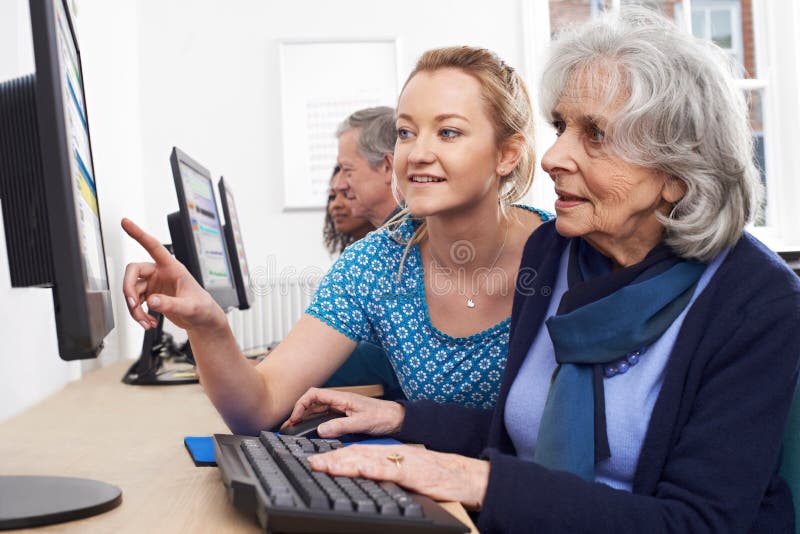 Tutor Helping Senior Woman In Computer Class