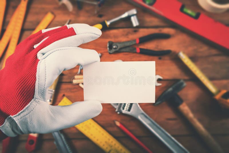 Tuttofare e servizi di riparazione domestici - mano che tiene biglietto da visita in bianco sopra gli strumenti del lavoro fotografie stock Tuttofare e servizi di riparazione domestici - mano che tiene biglietto da visita in bianco sopra gli strumenti del lavoro fotografie stock