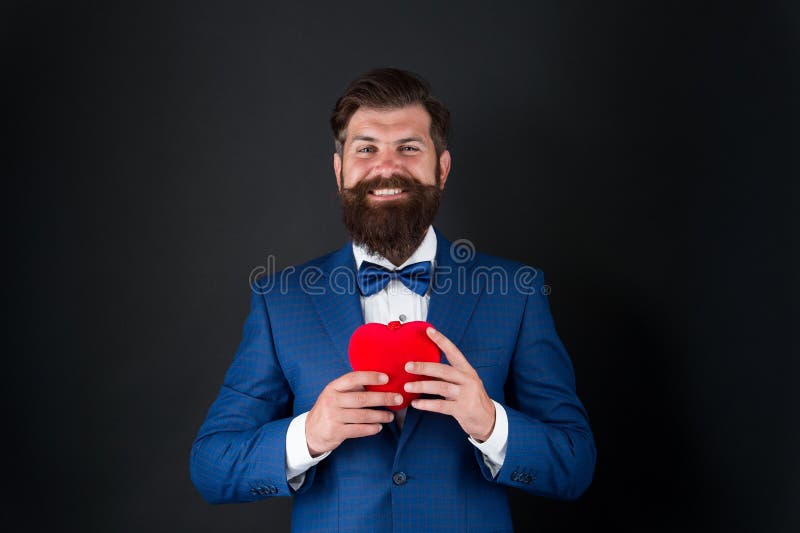 Tuxedo man with red heart. love and romance. ready for date. brutal bearded hipster in formal outfit. confident and royalty free stock images Tuxedo man with red heart. love and romance. ready for date. brutal bearded hipster in formal outfit. confident and royalty free stock images