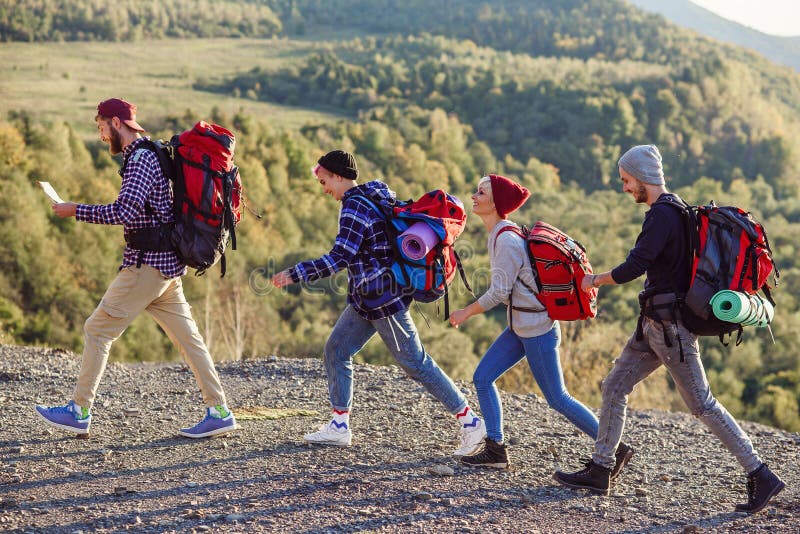 Tv? lyckliga par som g? r i bergen med? versikten Ung caucasian man med? versikten som v? ljer r? tt riktning Resor fotografering för bildbyråer