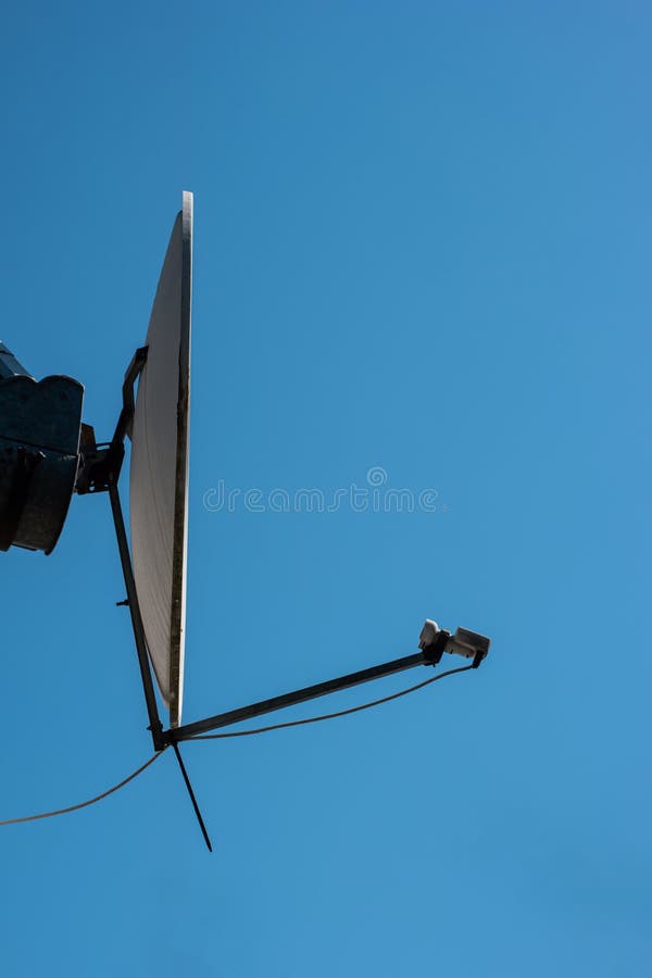 TV satellite dish receiver antenna mounted outside the house blue sky background.