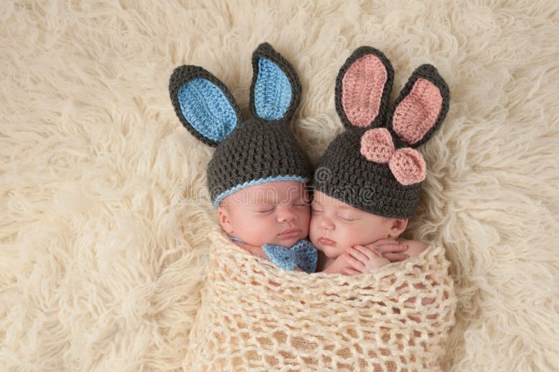 Sleeping 2 month old newborn baby twins wearing bunny costumes. They are swaddled together in a hugging position. Sleeping 2 month old newborn baby twins wearing bunny costumes. They are swaddled together in a hugging position.