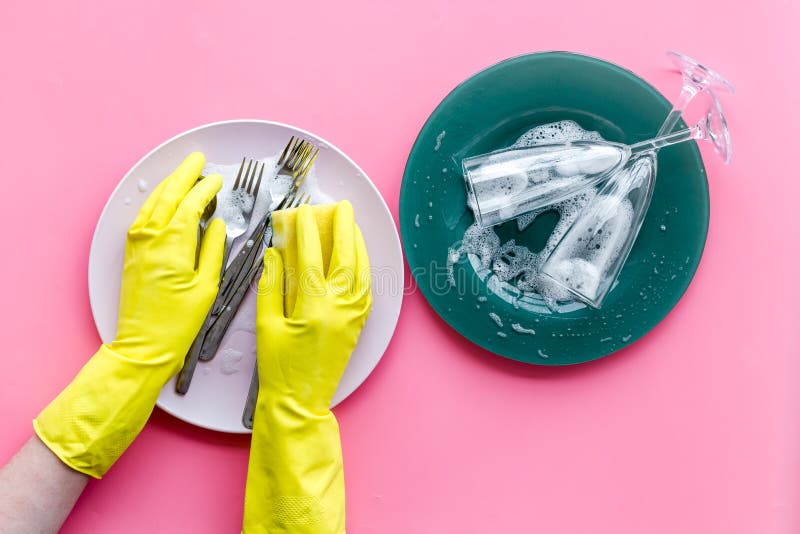 Tvättdiskar Handtag i gummihandskar och plåtar på rosa bakgrund royaltyfri foto Tvättdiskar Handtag i gummihandskar och plåtar på rosa bakgrund royaltyfri foto