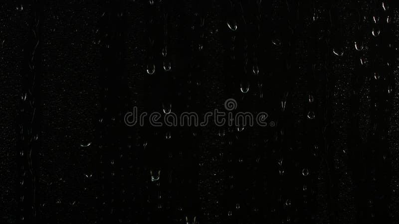 Tvättregn som faller ner på fönsterglas över svart bakgrund