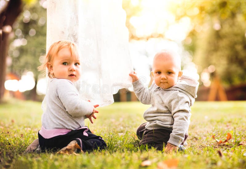 Två behandla som ett barn på gräset i trädgården fotografering för bildbyråer