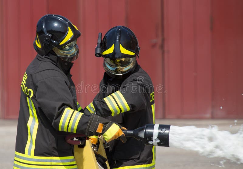 Två brandmän i handling med skum royaltyfri fotografi Två brandmän i handling med skum royaltyfri fotografi