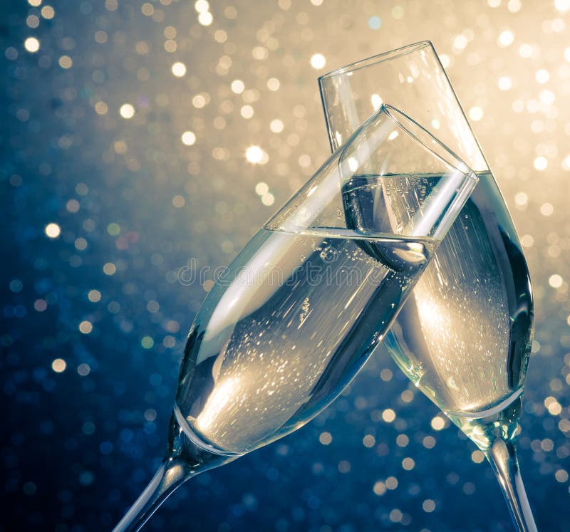 Två champagneflöjter med guld- bubblor på blå ljus bokehbakgrund arkivbilder Två champagneflöjter med guld- bubblor på blå ljus bokehbakgrund arkivbilder