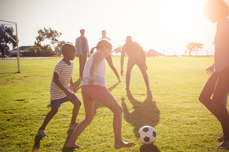 Två familjer som spelar fotboll i en parkera arkivbild Två familjer som spelar fotboll i en parkera arkivbild