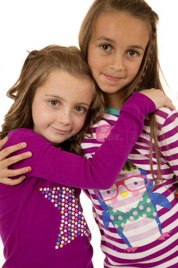 Two girl cousins wearing christmas pajamas hugging. Two girl cousins wearing christmas pajamas hugging