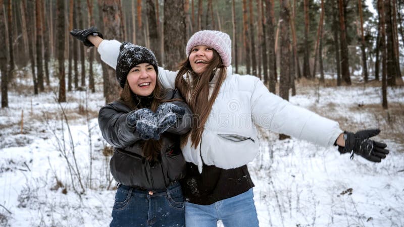 Två glada tonårsflickor som har kul och skrattar i skogen på vinterdagen. människor som leker utomhus under vintersemestern och royaltyfri bild