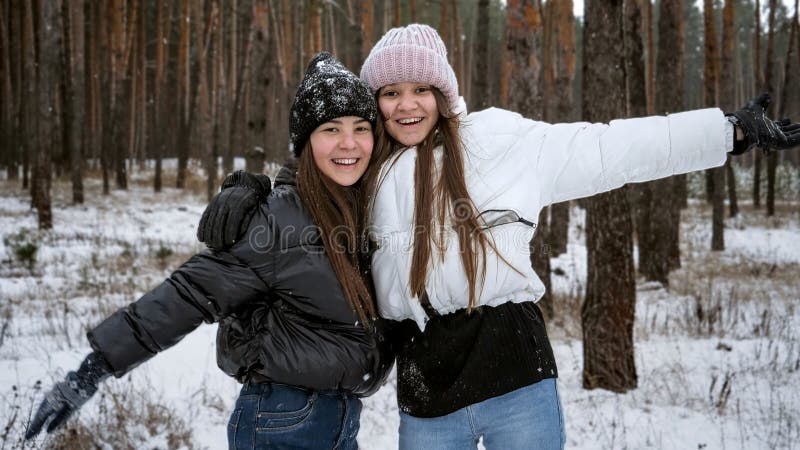Två glada tonårsflickor som skrattar och fuskar på grund av den första snön. Personer som leker utomhus under vintersemester och s fotografering för bildbyråer