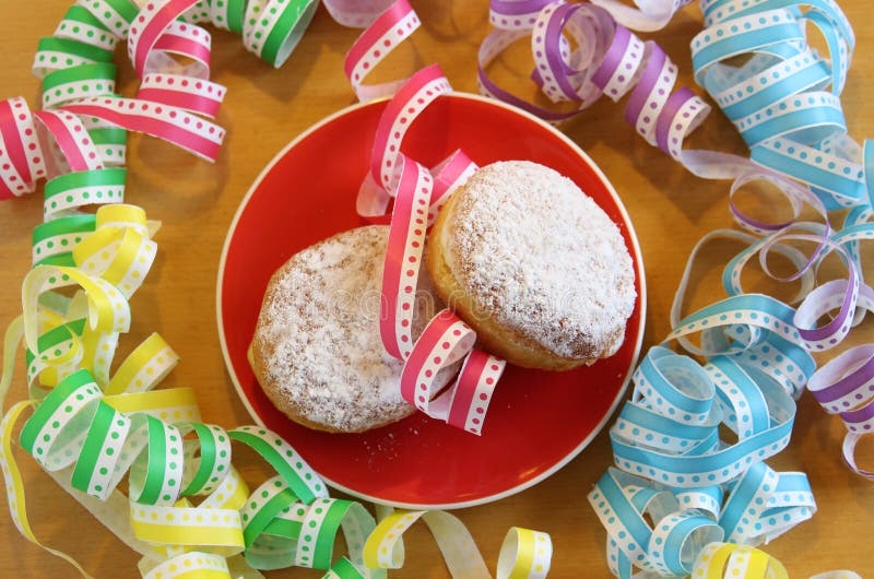 Två karnevaldonuts på en platta med mång- kulör streame arkivfoton Två karnevaldonuts på en platta med mång- kulör streame arkivfoton