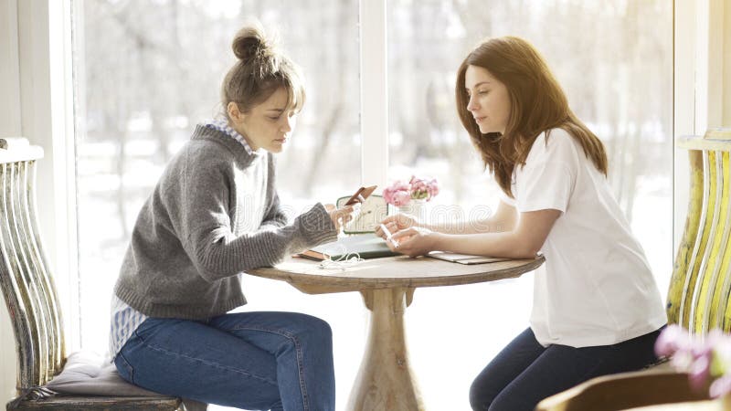 Två kvinnliga vänner som sitter i en kaféframsida - till - framsida arkivbild Två kvinnliga vänner som sitter i en kaféframsida - till - framsida arkivbild