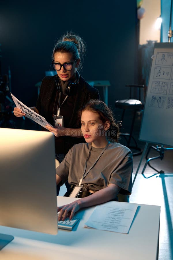 Vertical portrait of two women working in video production crew and using computer reviewing footage on set. Vertical portrait of two women working in video production crew and using computer reviewing footage on set