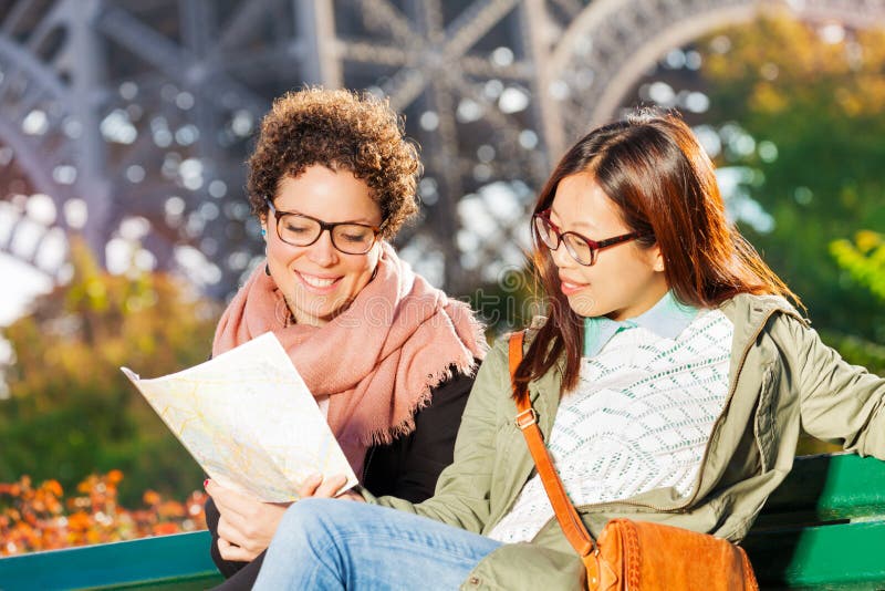 Två kvinnor som sitter på bänk med den pappers- översikten av Paris fotografering för bildbyråer Två kvinnor som sitter på bänk med den pappers- översikten av Paris fotografering för bildbyråer
