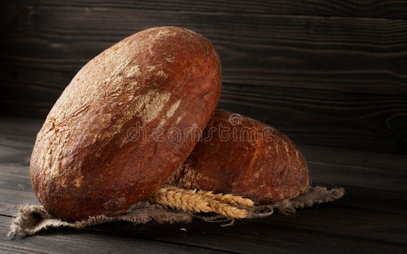 Två loaves av nytt rågbröd med öron av vete arkivfoto Två loaves av nytt rågbröd med öron av vete arkivfoto